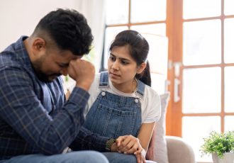 A young woman encourages and holds the hand of her worried husband. is having a hard time making some decisions..